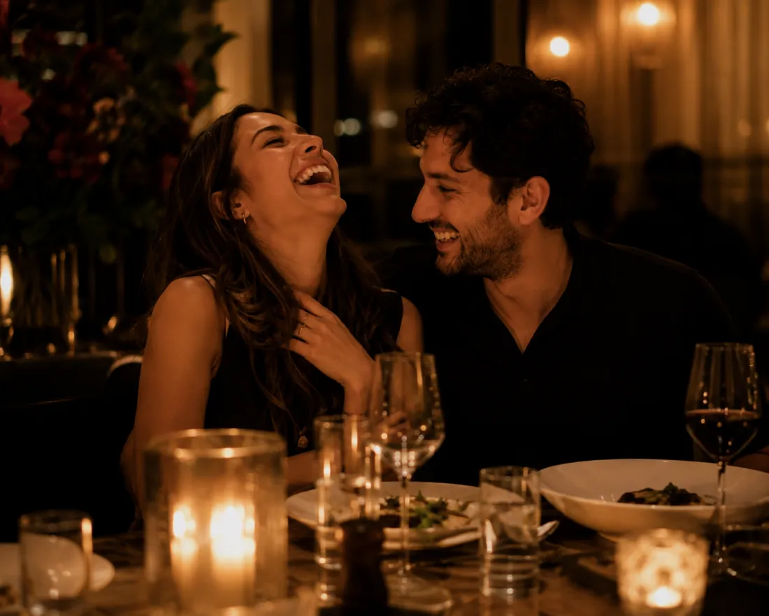 A couple laughing together over dinner at a candlelit restaurant
