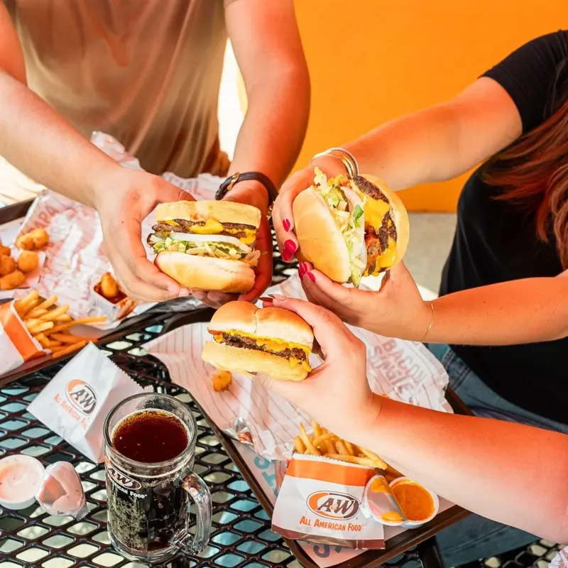 Hands holding A&W burgers at a Vancouver A&W Canada location
